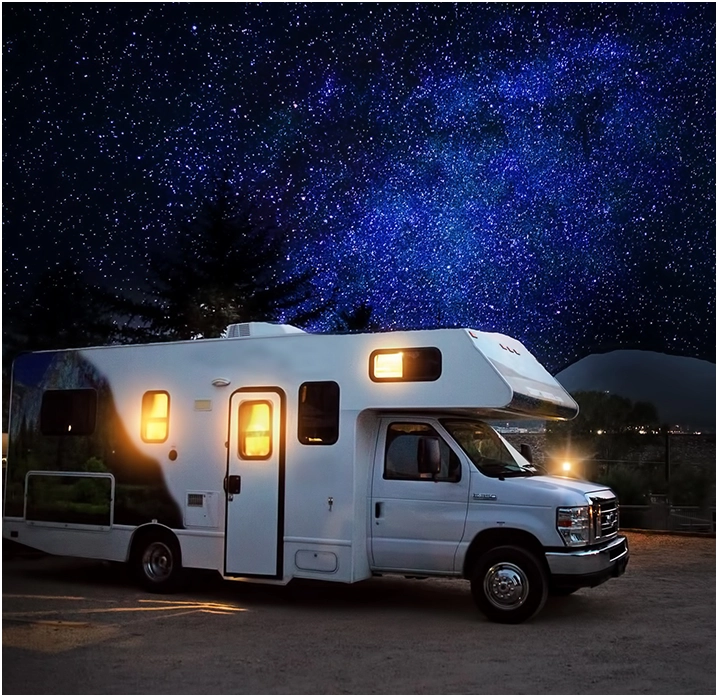 A white rv parked in the dark under a night sky.